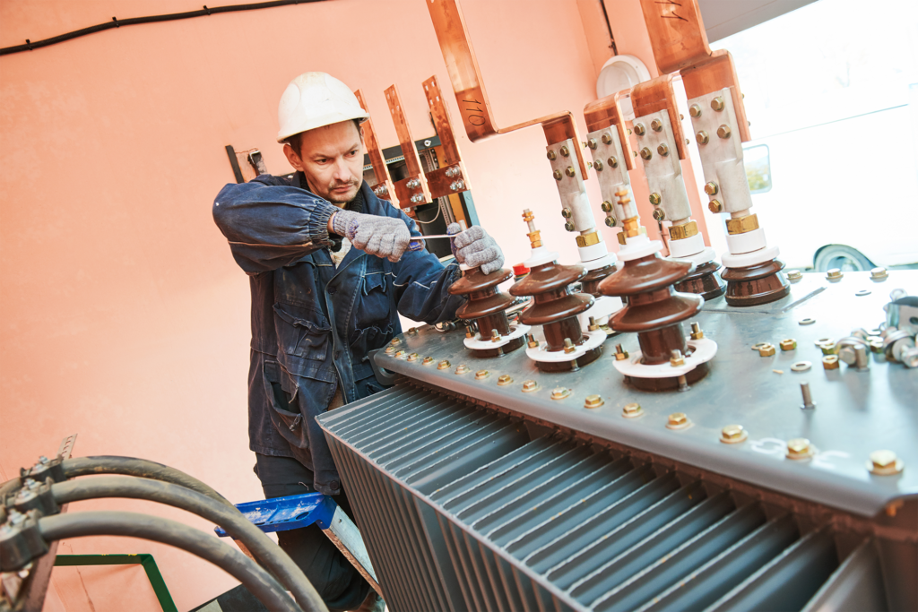 Electrician lineman worker installing power industrial transformer