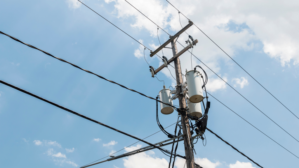 Power line pole with a transformer on it. Typical wooden post from USA